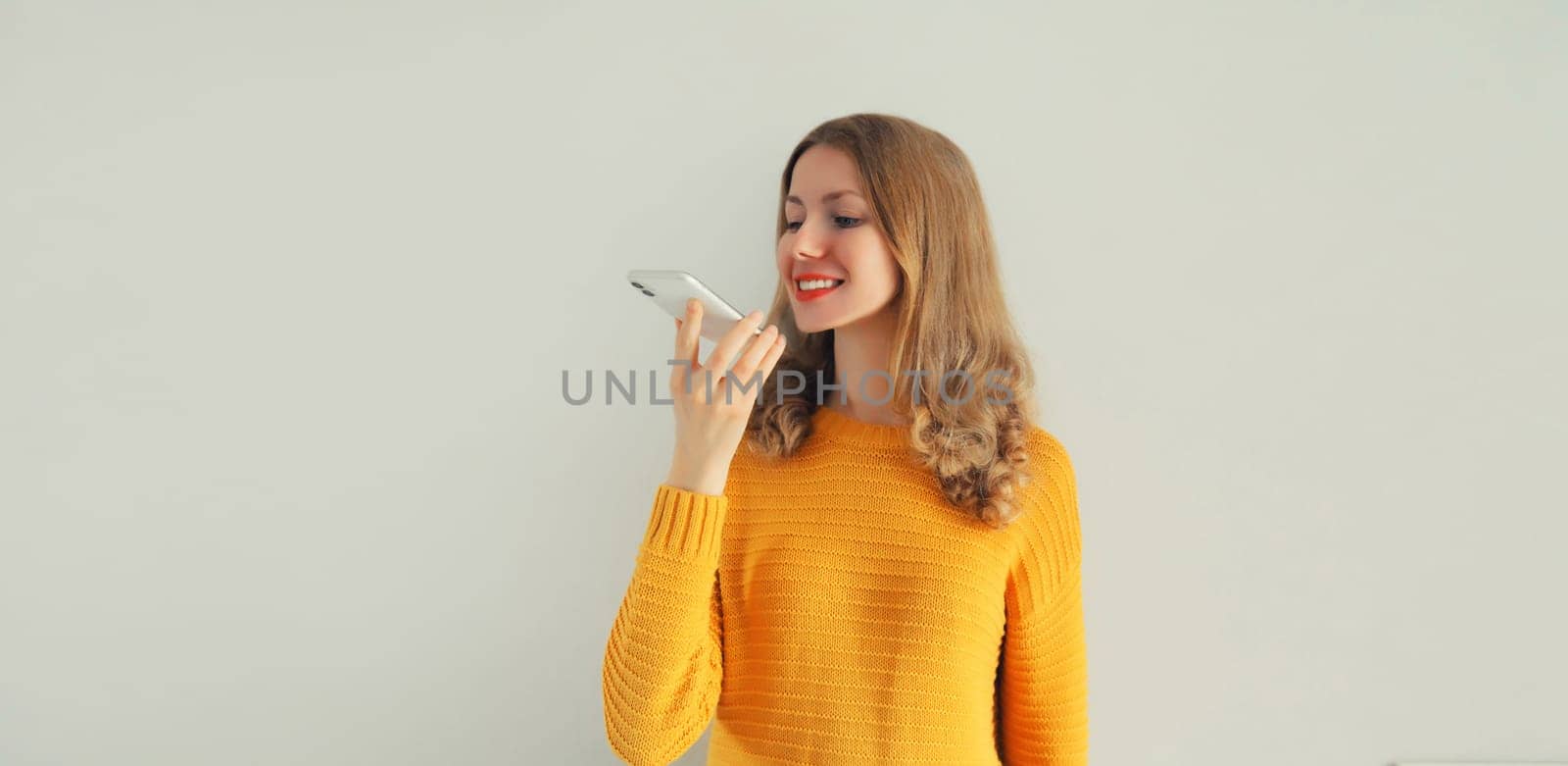 Happy young woman using voice command recorder, assistant or takes calling on gray background