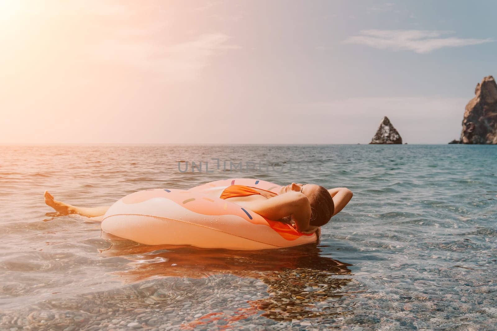 Summer Vacation Woman in hat floats on an inflatable donut mattress, a water toy swim ring. Unrecognizable young woman relaxing and enjoying family summer travel holidays vacation on the sea