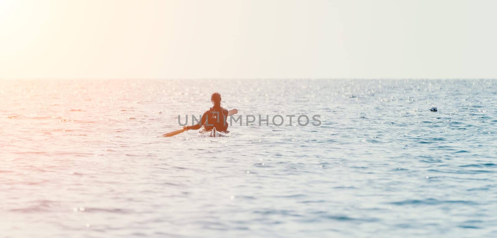 Happy smiling woman in kayak on ocean, paddling with wooden oar. Calm sea water and horizon in background