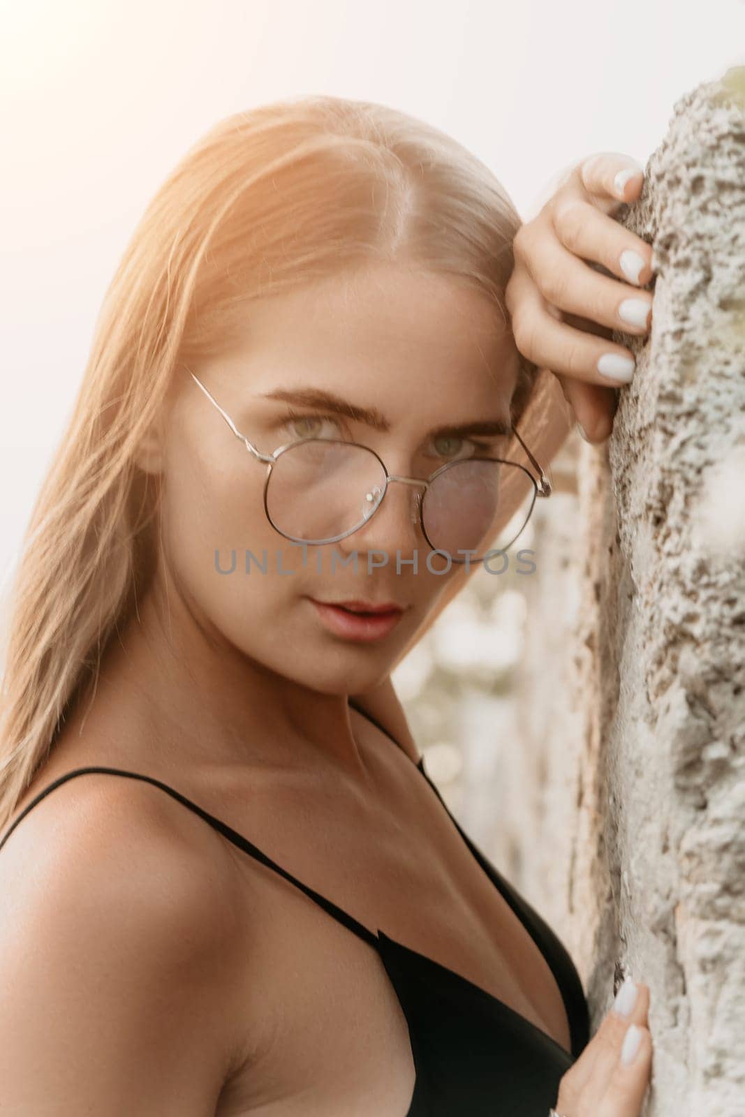 Woman travel sea. Young Happy woman in a long red dress posing on a beach near the sea on background of volcanic rocks, like in Iceland, sharing travel adventure journey