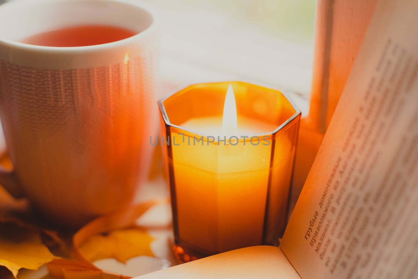 A burning candle on the window is autumn . the comfort of home . autumn comfort . autumn mood. The chondra .