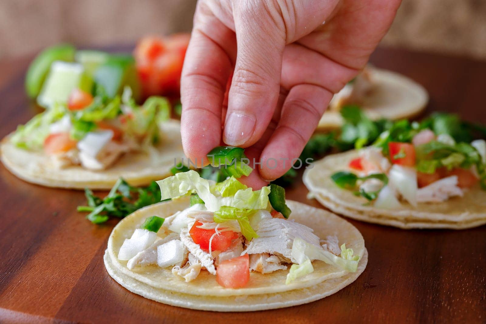 A close up studio photo of putting chopped peppers on a street taco.