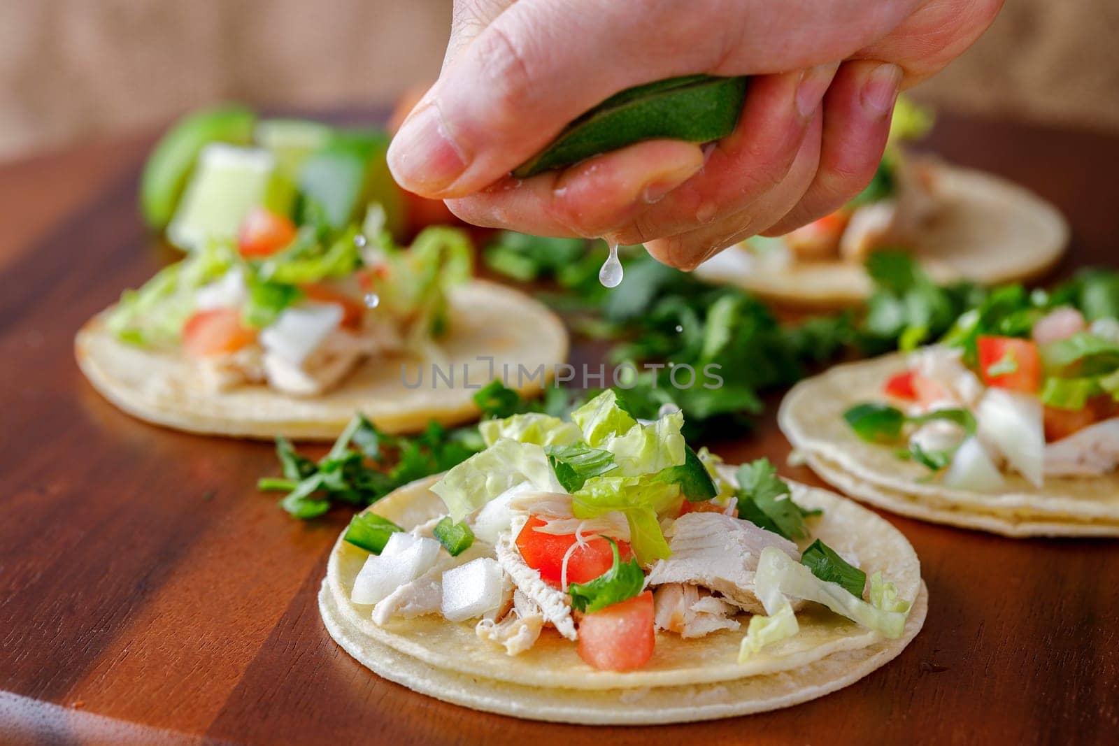 Squeezing lime juice on a finished street taco in a studio setting.