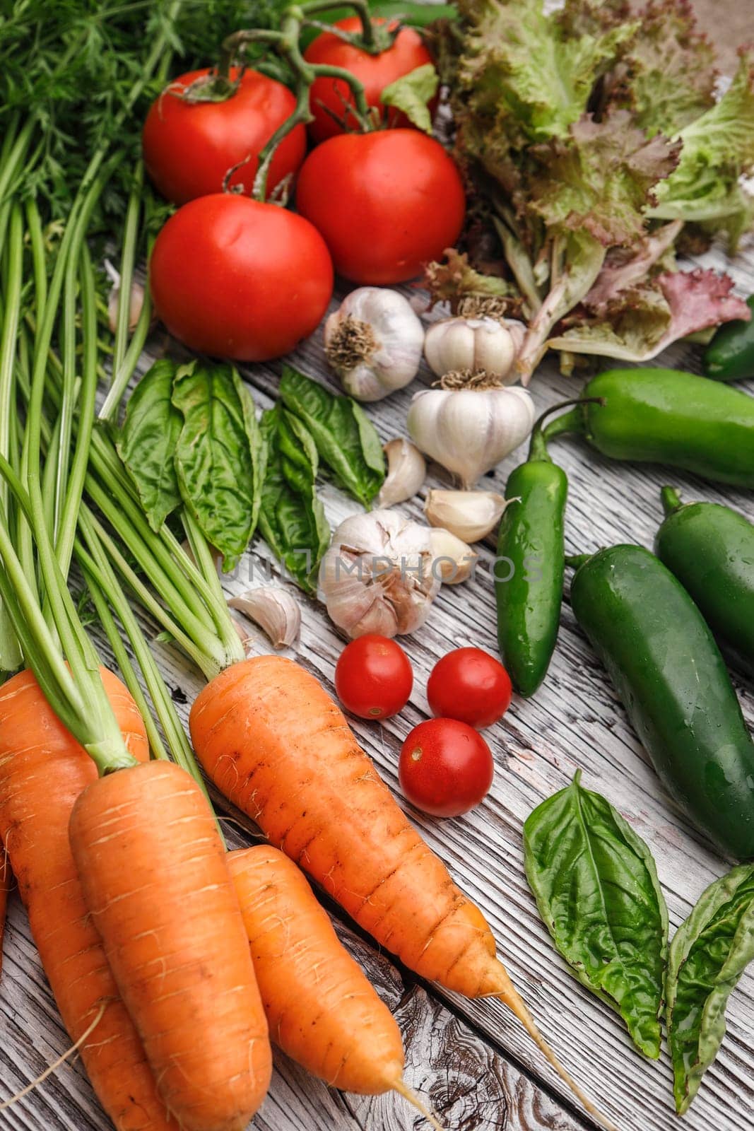 An overview of assorted vegetables and basil on a wooden table.