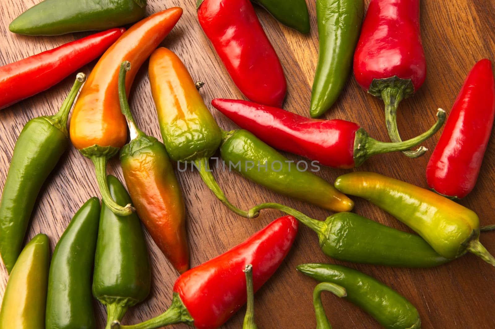 An overview of ripe red and green peppers on a table.