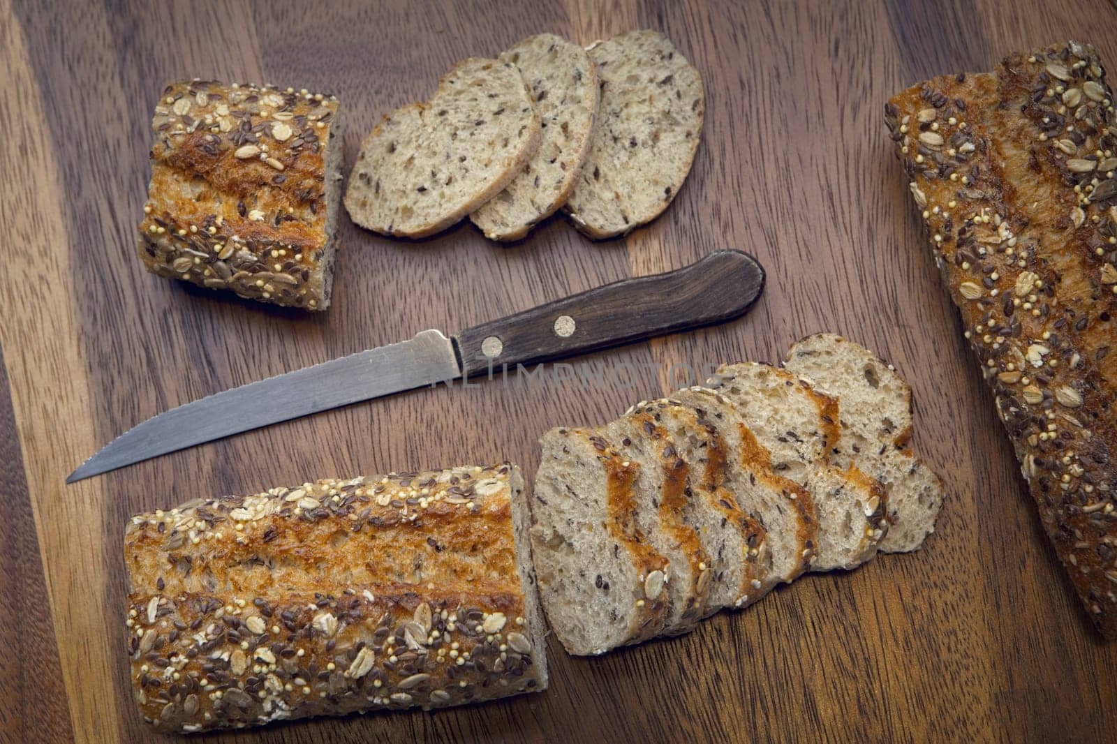 An overview of whole grain baguette and baguette slices with a knife.