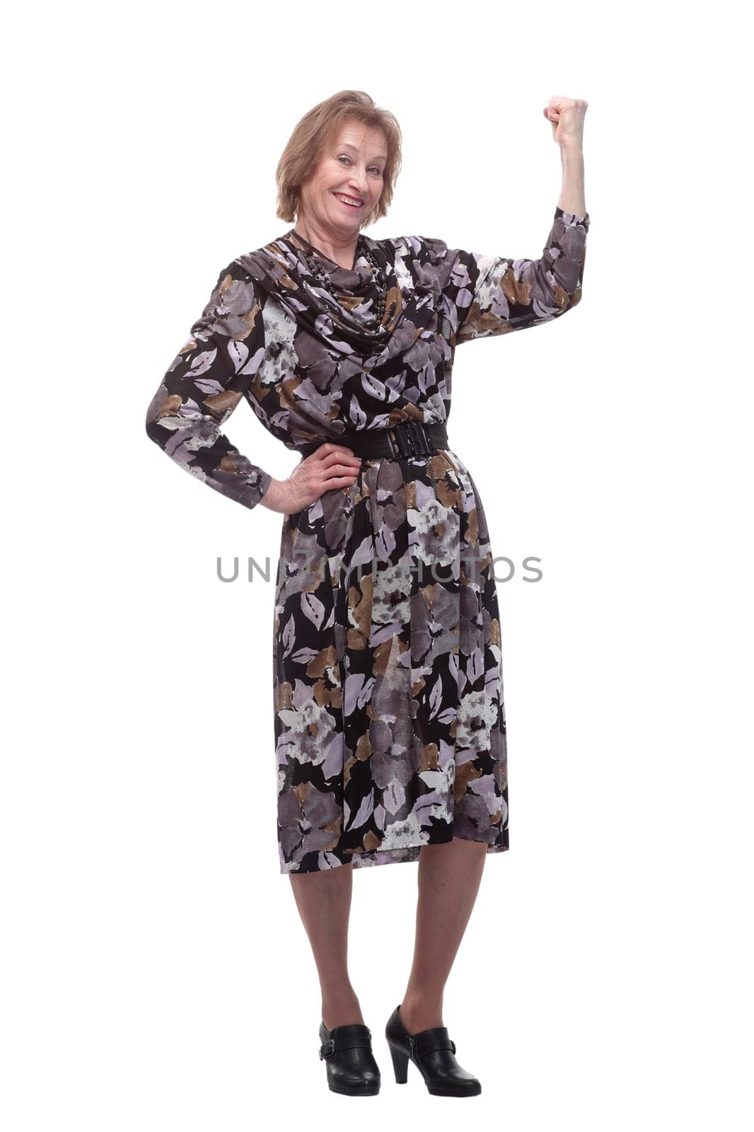 Elderly woman keeping arm raised and looking at camera while standing isolated on white background. Concept of winner