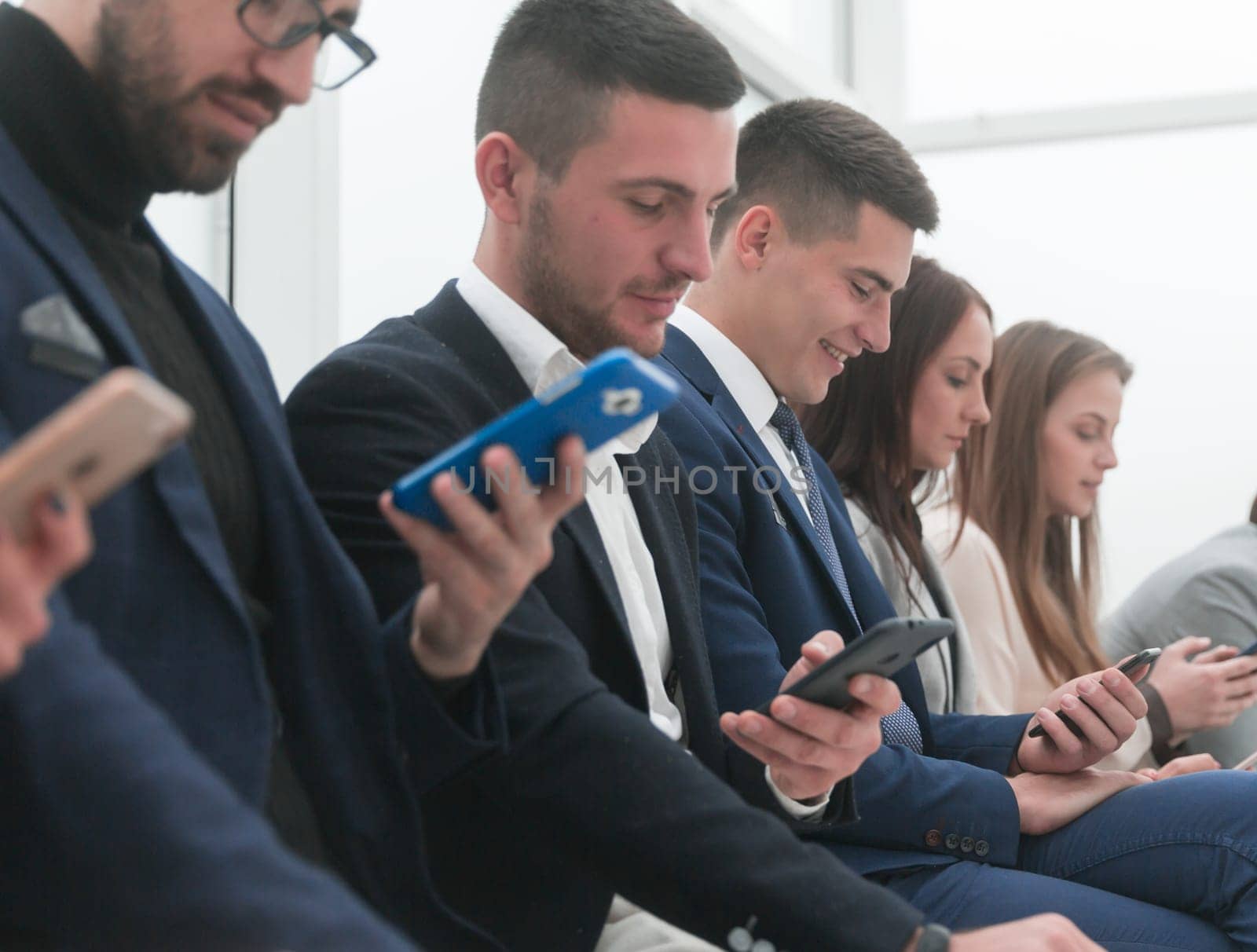 group of young business people looking at their smartphone screens. by asdf