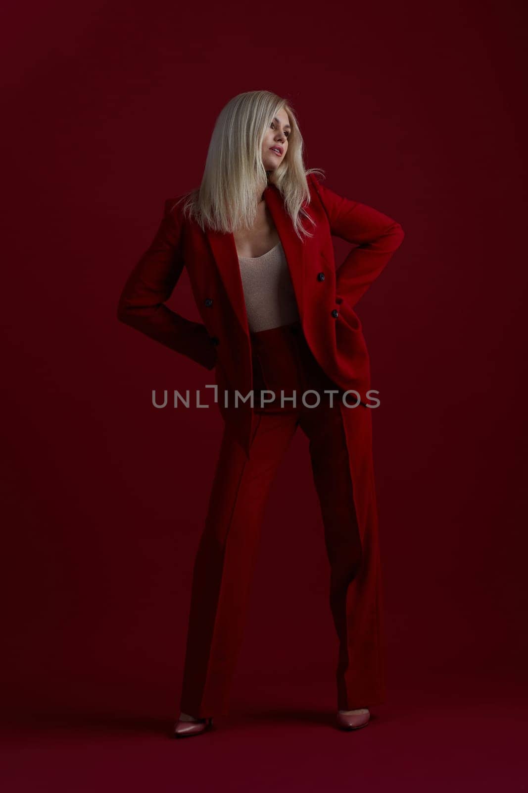 Portrait of a blonde woman in red dress on a red background