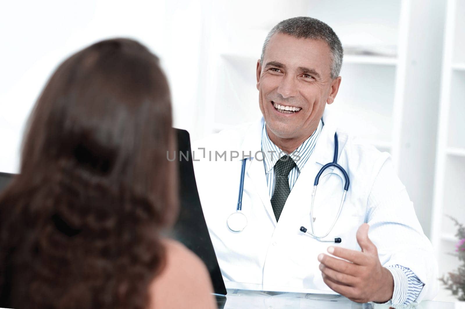 Doctor talking to patient sitting at the table by asdf