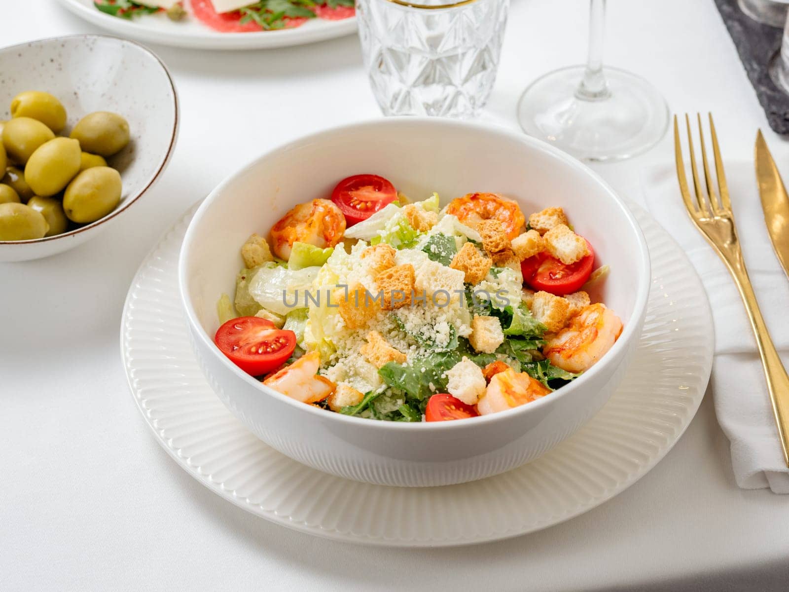 Caesar salad with shrimps on restaurant table by fascinadora