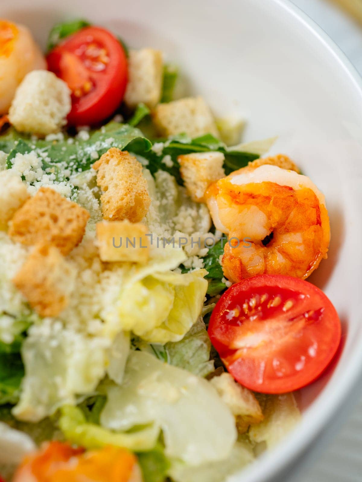 Caesar salad with shrimps on plate closeup view