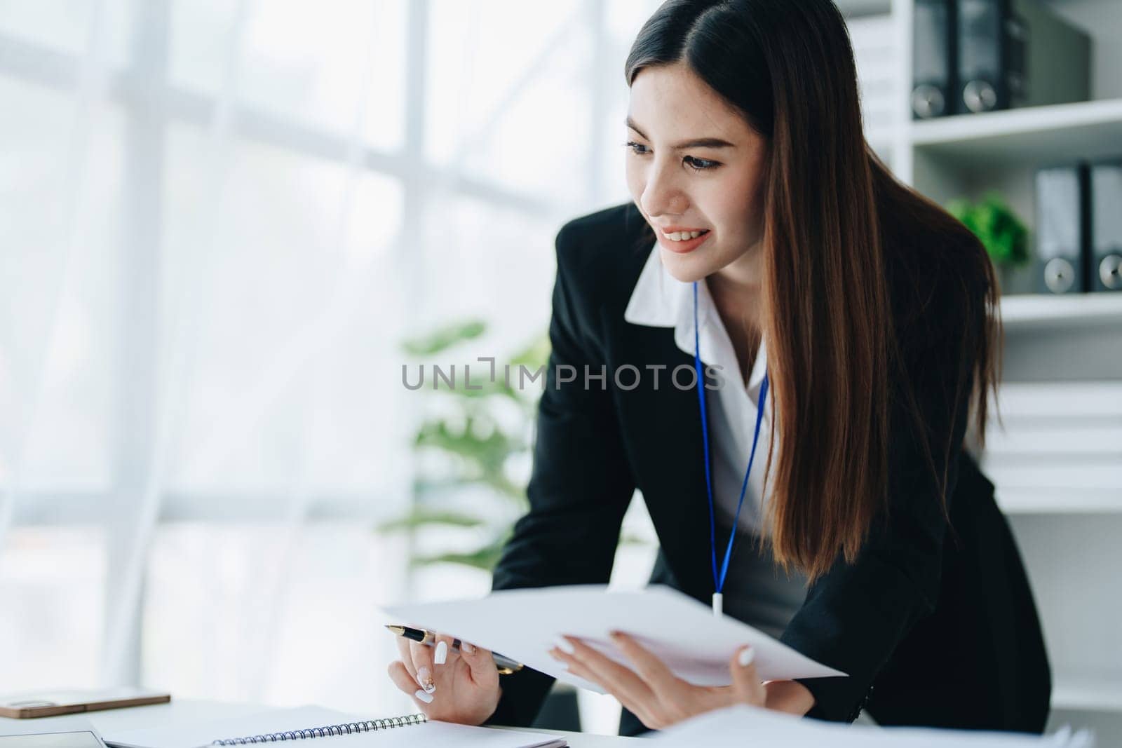 Beautiful young teen asian businesswoman using laptop computer and paperworks with planning working on financial document, tax, exchange, accounting and Financial advisor by Manastrong