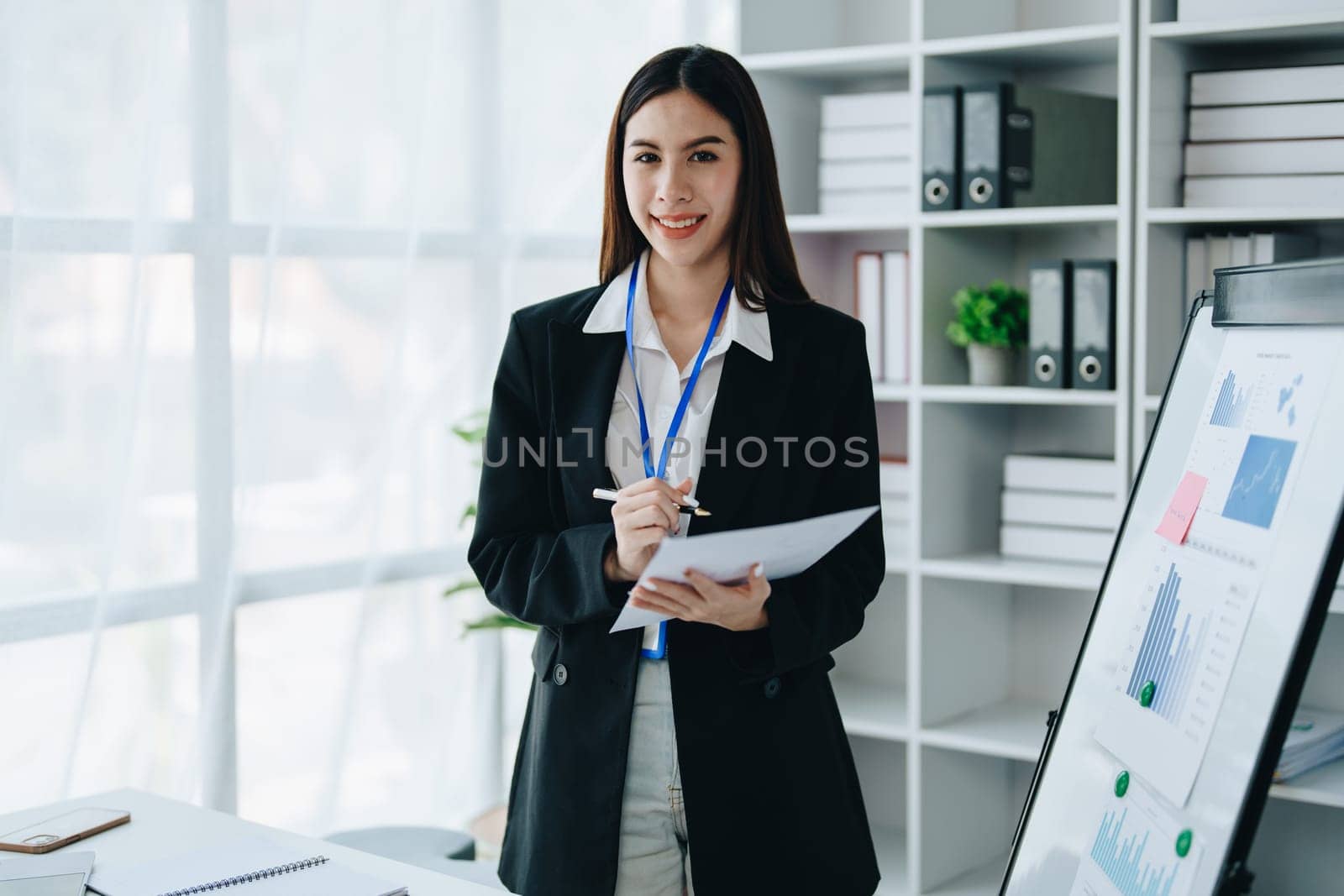 Portrait of young asian woman holding notebook with presentation of strategy, investment plan and marketing. by Manastrong