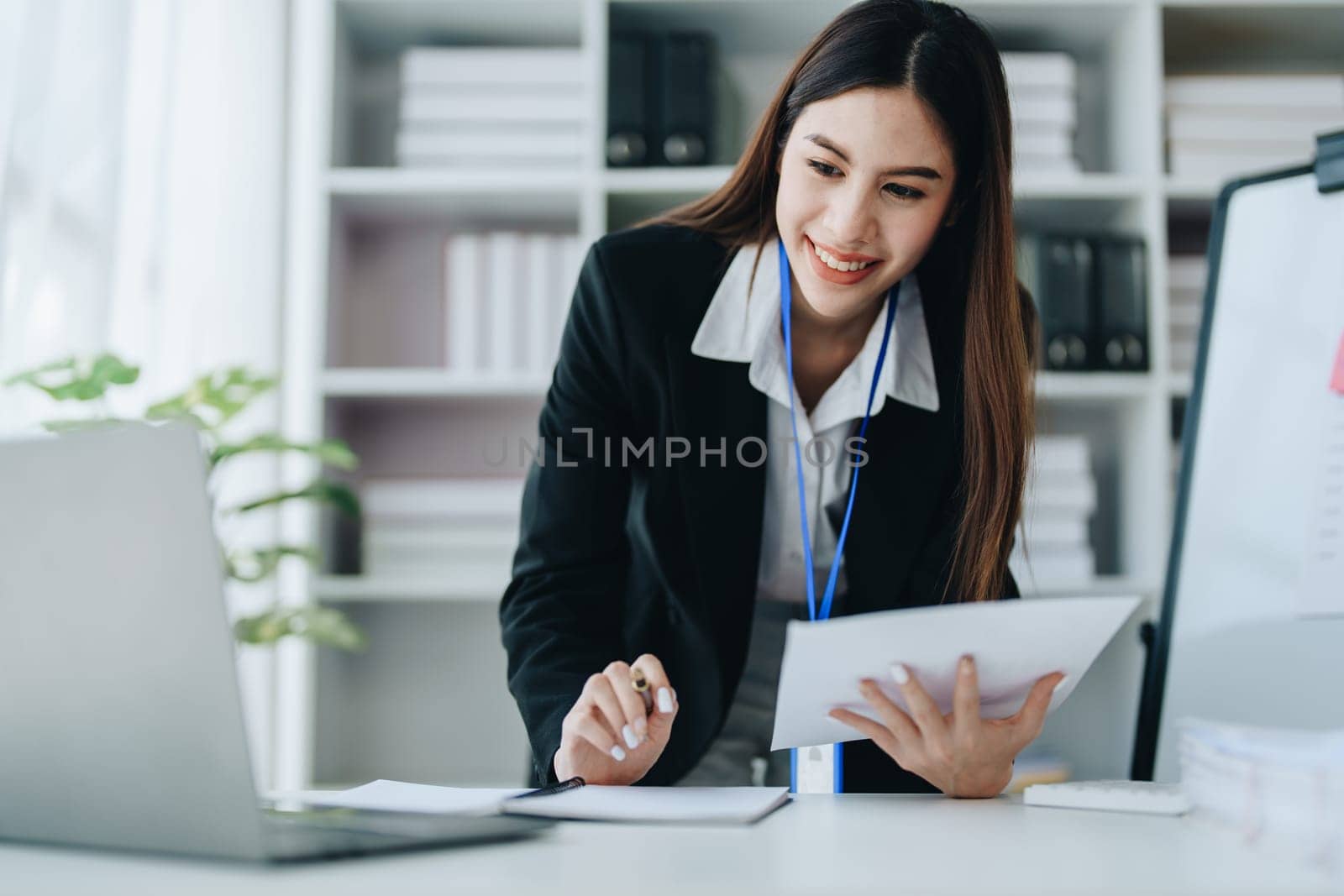 Beautiful young teen asian businesswoman using laptop computer and paperworks with planning working on financial document, tax, exchange, accounting and Financial advisor.