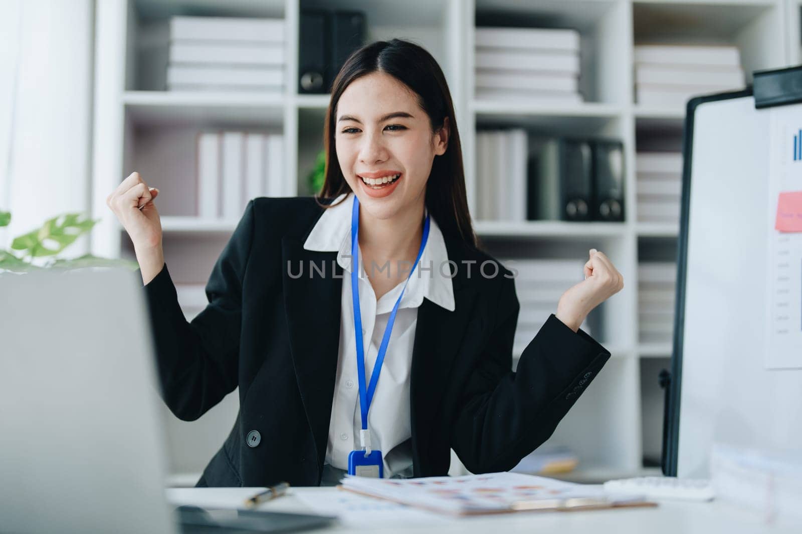 Portrait of a male business owner showing a happy smiling face as he has successfully invested his business using computers and financial budget documents at work.