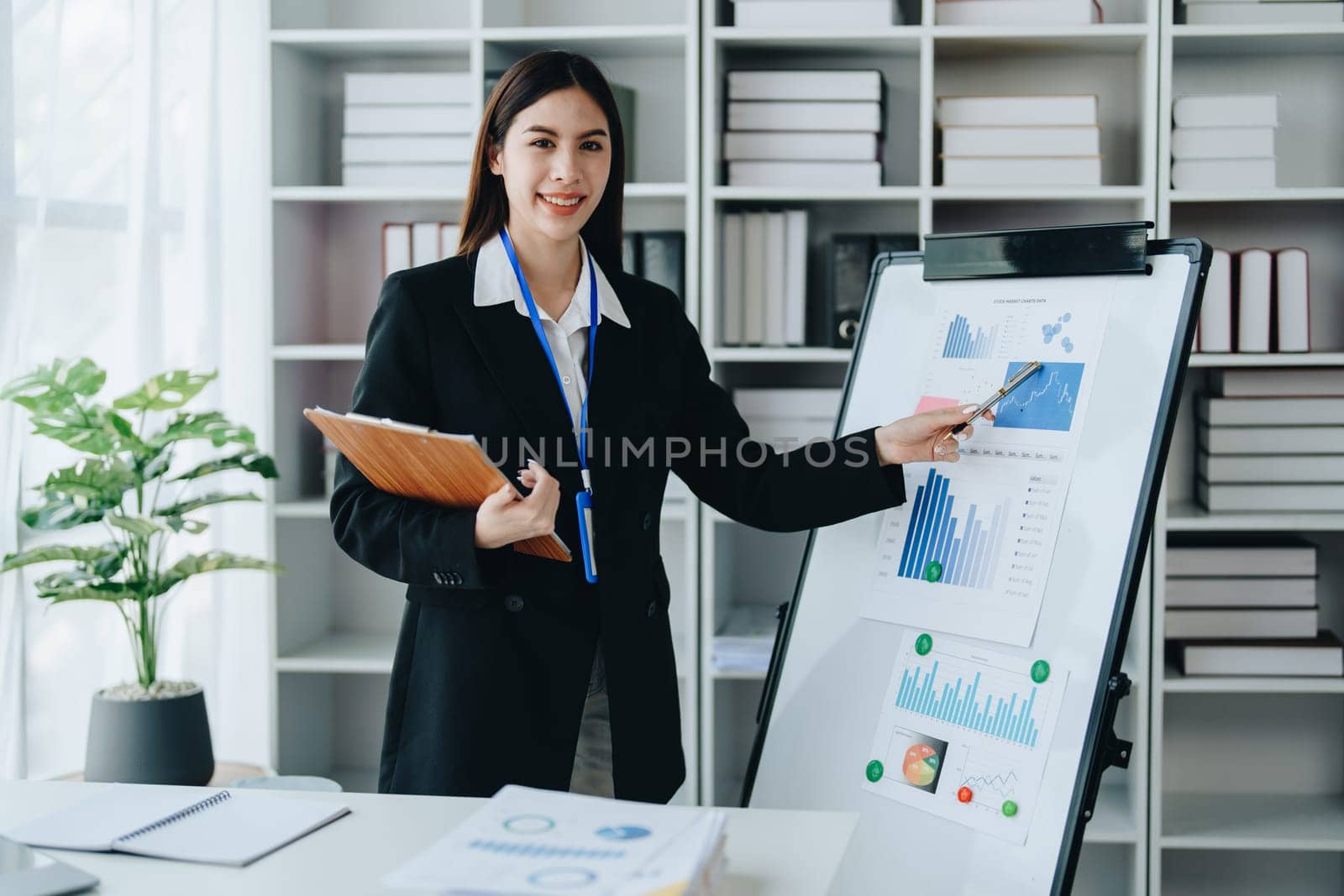 Portrait of young asian woman holding notebook with presentation of strategy, investment plan and marketing