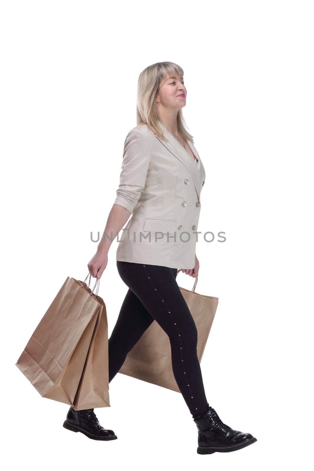 in full growth. happy mature woman with shopping bags walking home . isolated on a white background.