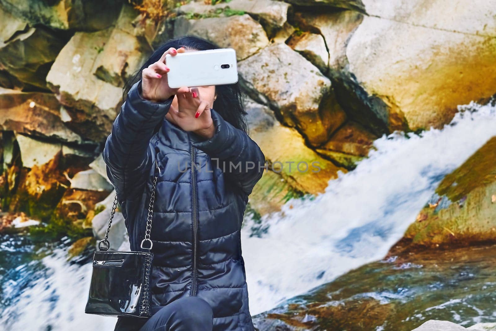 A young woman takes a selfie near a rocky mountain river with a rapid flow by jovani68