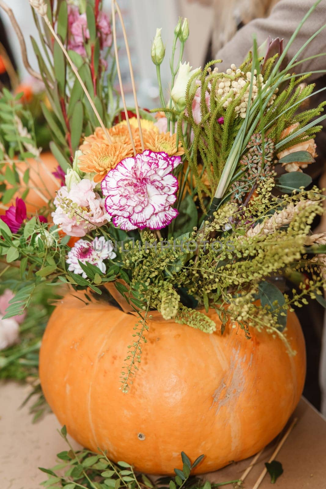 Flower arrangement in a pumpkin, autumn interior decor. Creating handmade autumn decor