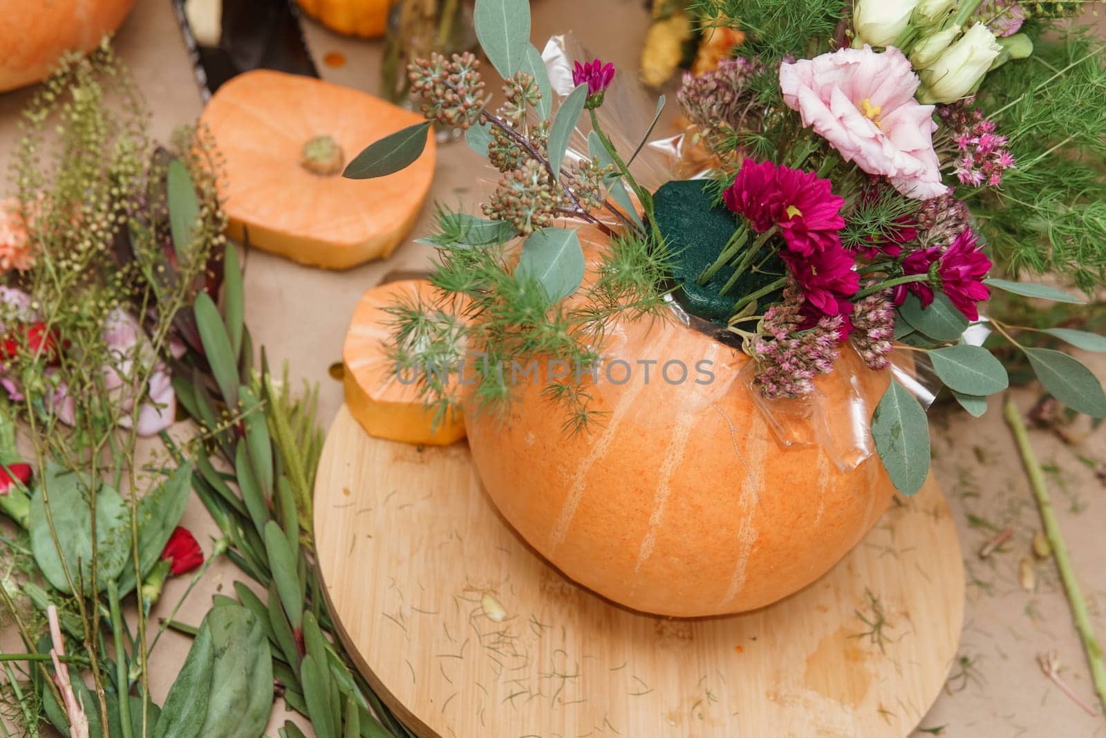 Flower arrangement in a pumpkin, autumn interior decor. Creating handmade autumn decor