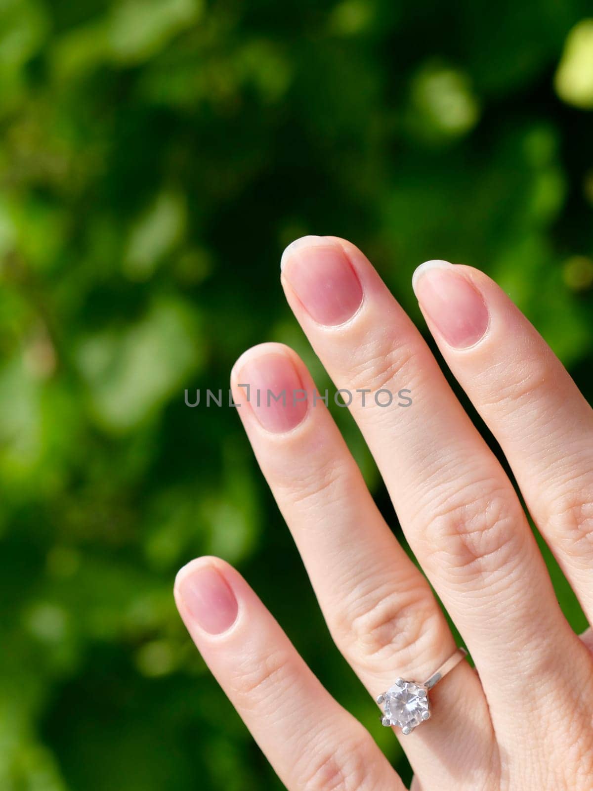 Japanese hygienic manicure on the female hand of the bride with a wedding ring. Clean and safe manicure. Beautiful fingers and nails without gel polish. Vertical
