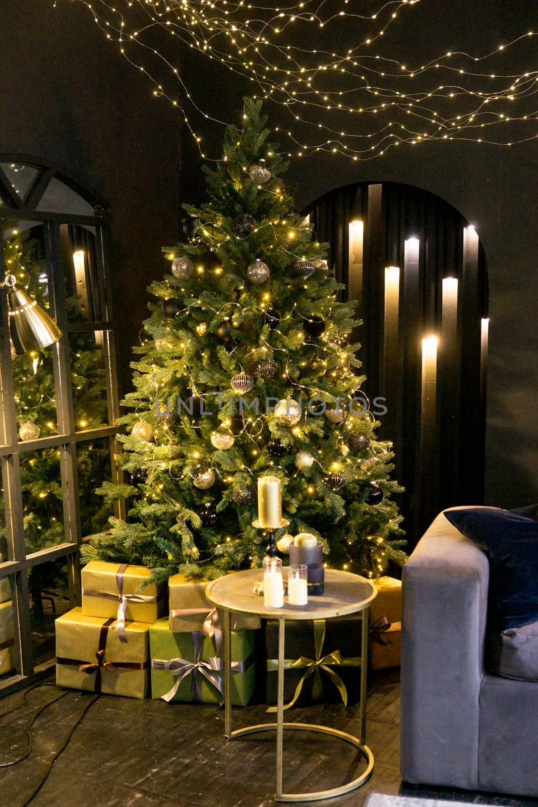 Christmas interior with a beautiful Christmas tree, sofa, light bulbs and dark background