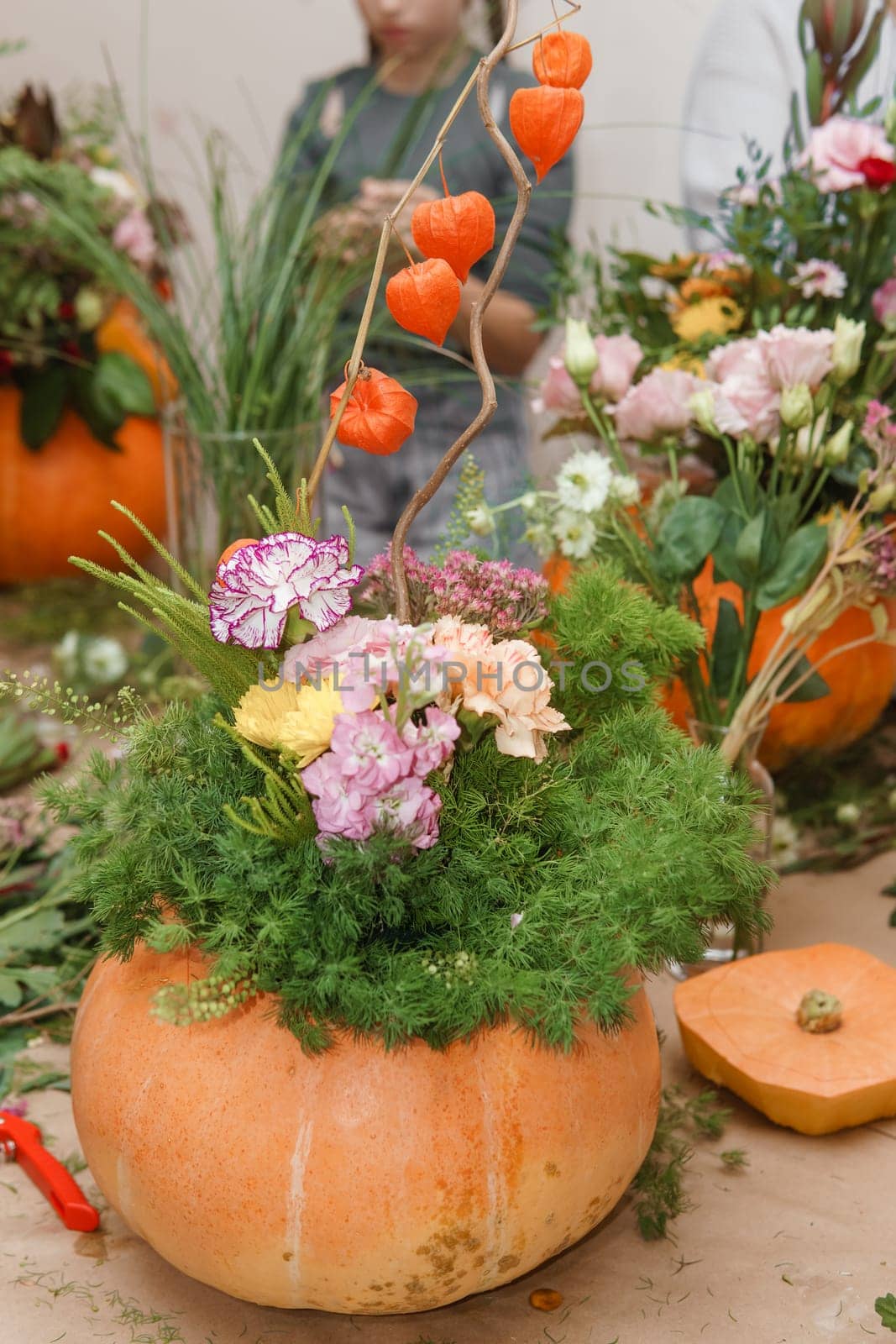 Flower arrangement in a pumpkin, autumn interior decor. Creating handmade autumn decor