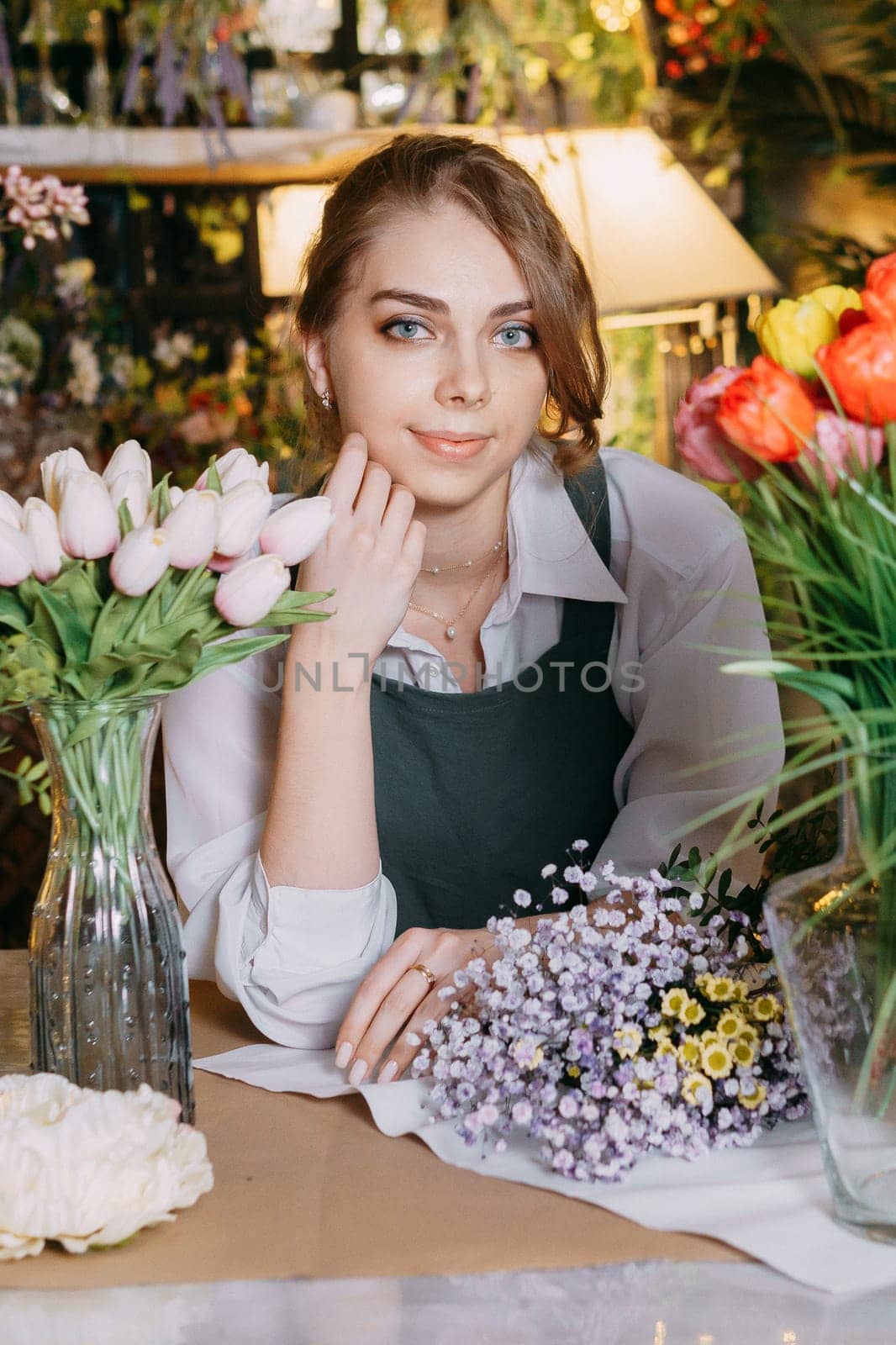 A woman in her florist shop collects bouquets of flowers. The concept of a small business. Bouquets of tulips for the holiday on March 8