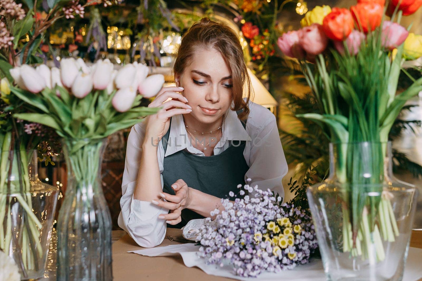 A woman in her florist shop collects bouquets of flowers. The concept of a small business. Bouquets of tulips for the holiday on March 8