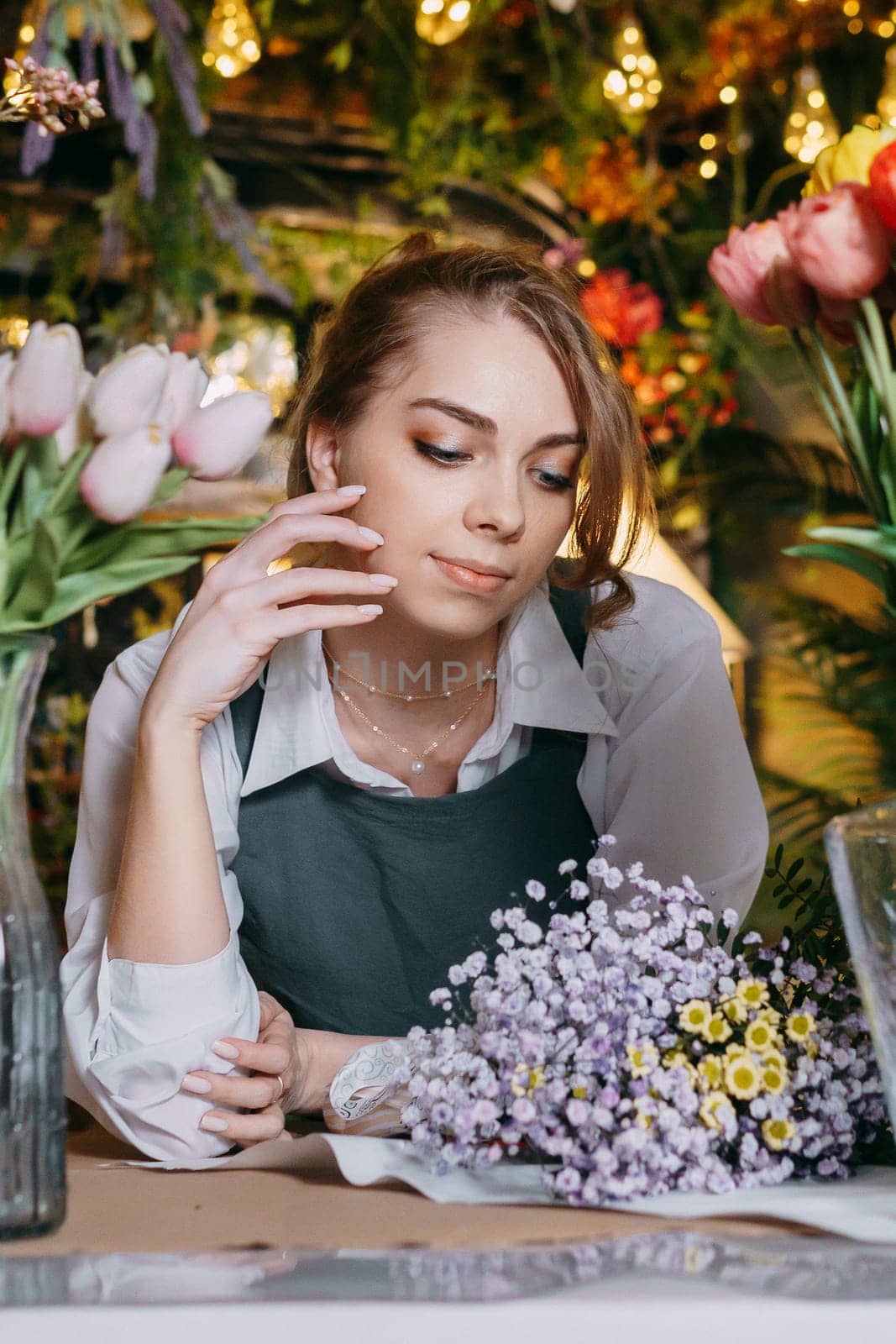 A woman in her florist shop collects bouquets of flowers. The concept of a small business. Bouquets of tulips for the holiday on March 8