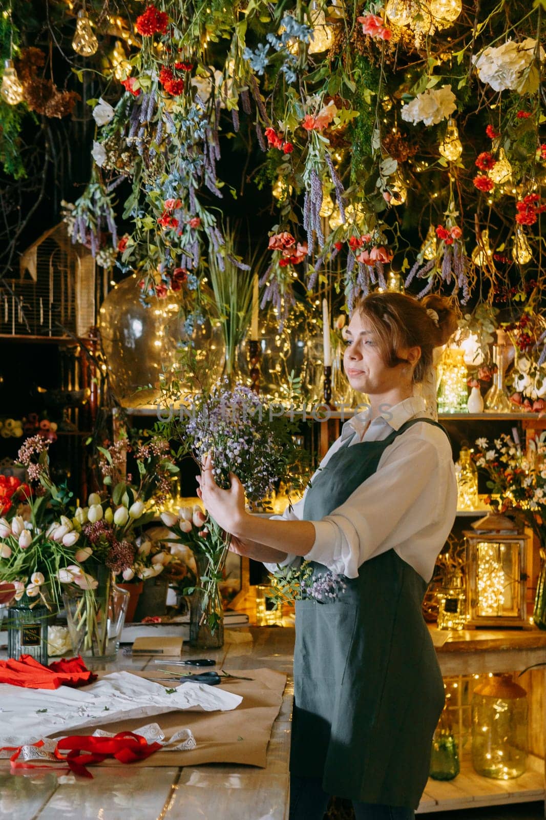 A woman in her florist shop collects bouquets of flowers. The concept of a small business. Bouquets of tulips for the holiday on March 8