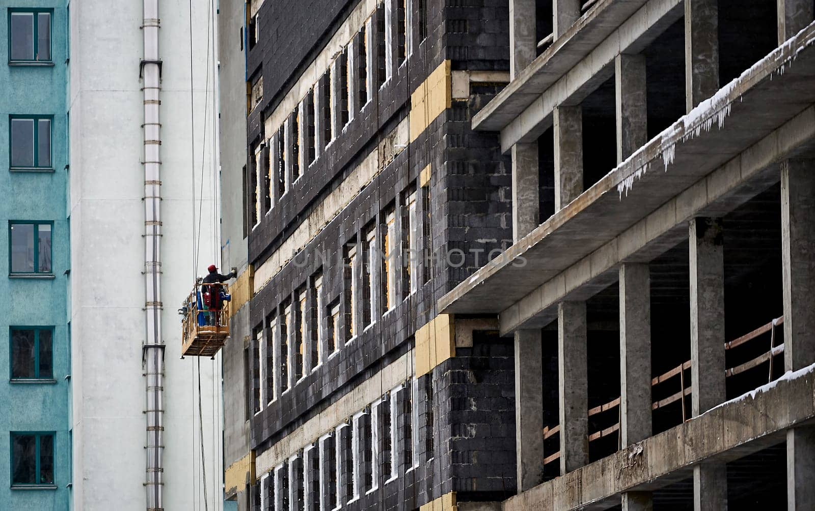 a construction worker makes a structure for a ventilation facade on a building using a screwdriver