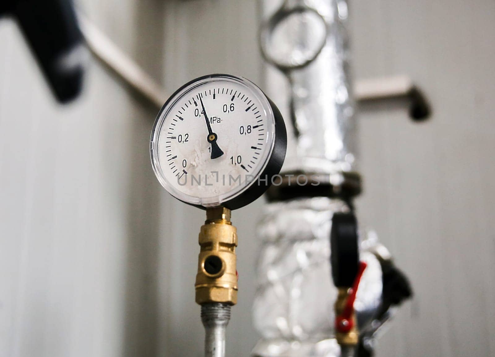 Closeup of manometer, pipes and faucet valves of heating system in a boiler room