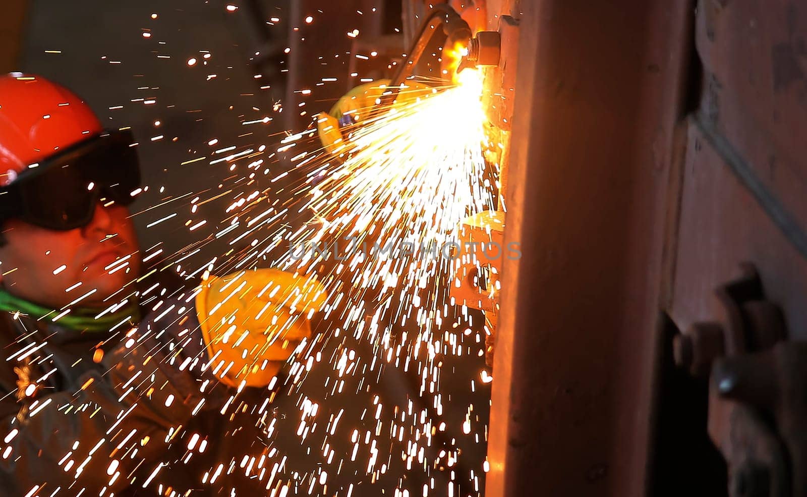 Sparks and droplets of molten metal during the work of the welder. Repair of wagons in the depot.