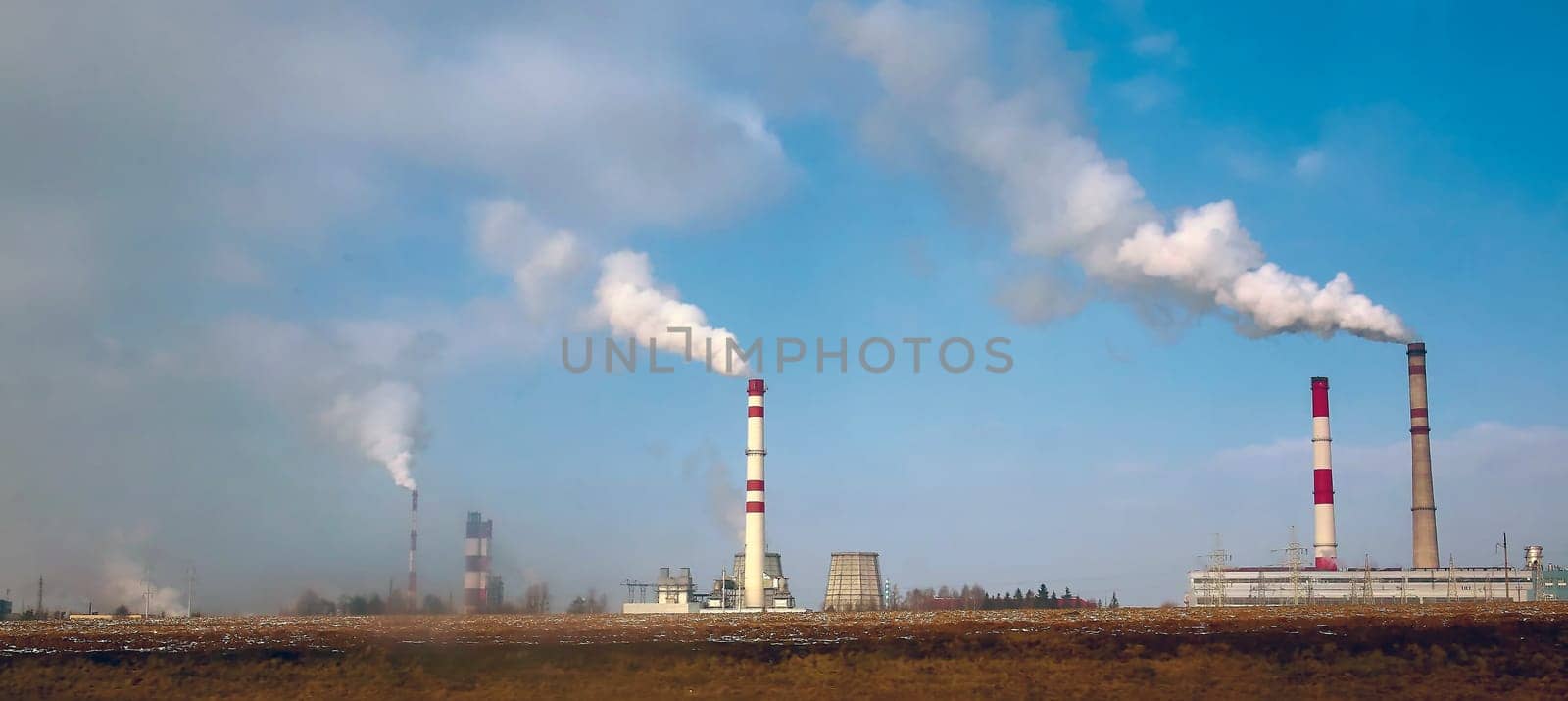 Chemical plant, pipes and smoke, air pollution. Early morning and clear skies.