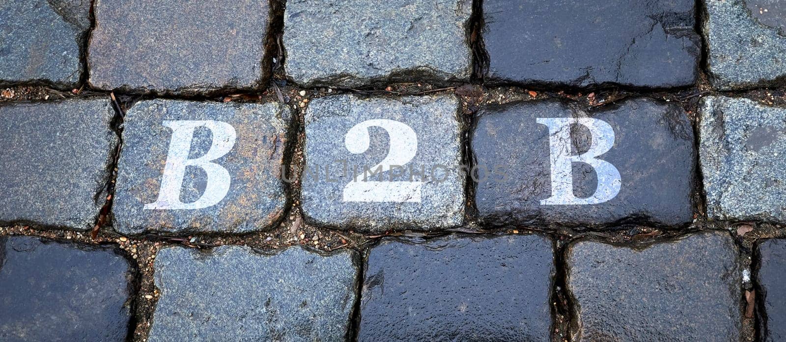 B2B is written on a wet stone gray wall in big letters. Background image.