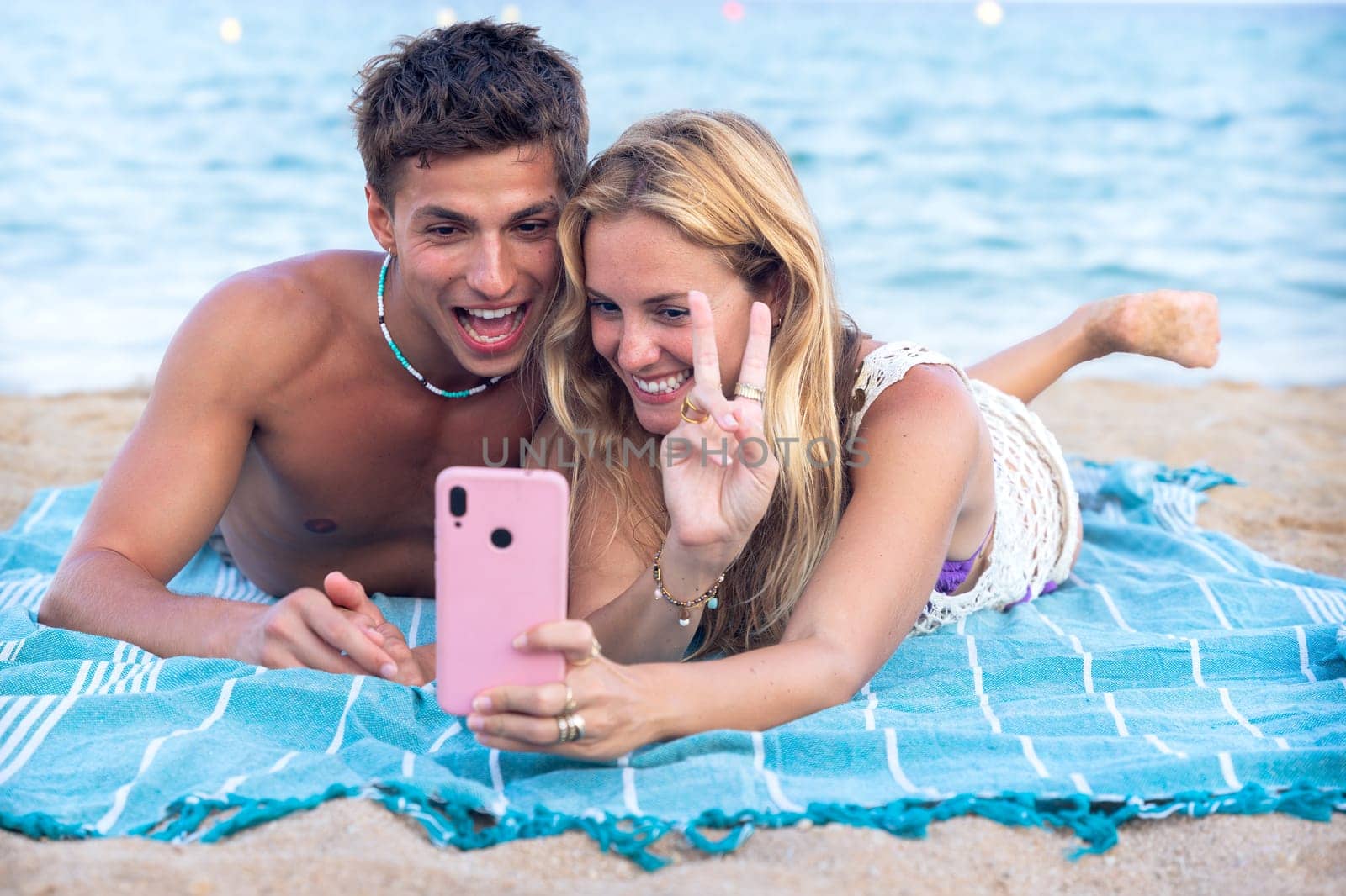 Smiling young woman and man enjoying vacation. Beautiful and cheerfulcoupleof generation z pose for a photo with a mobile phone.