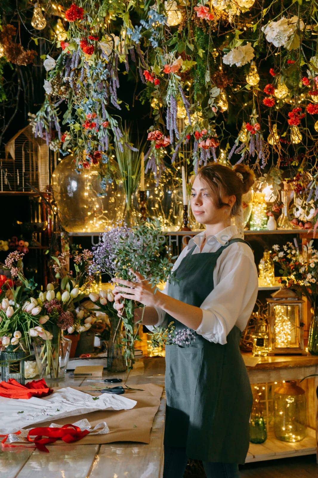 A woman in her florist shop collects bouquets of flowers. The concept of a small business. Bouquets of tulips for the holiday on March 8