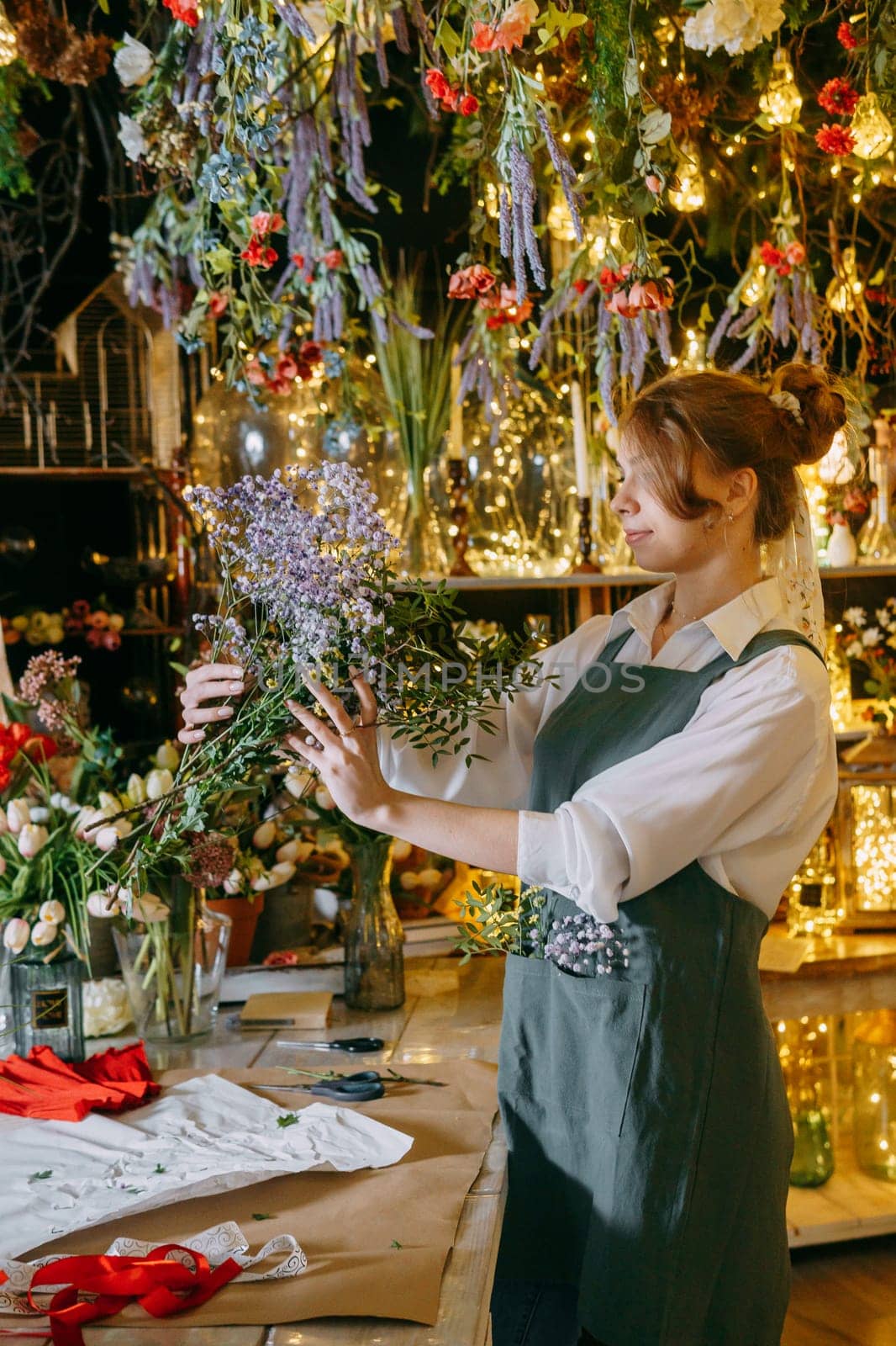 A woman in her florist shop collects bouquets of flowers. The concept of a small business. Bouquets of tulips for the holiday on March 8