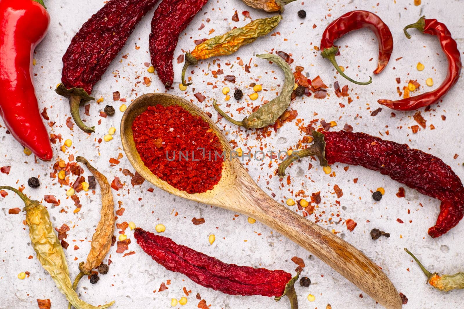 A flat lay photo of peppers in various stages. Fresh, drying, dried, pepper flakes, and pepper powder in a spoon.