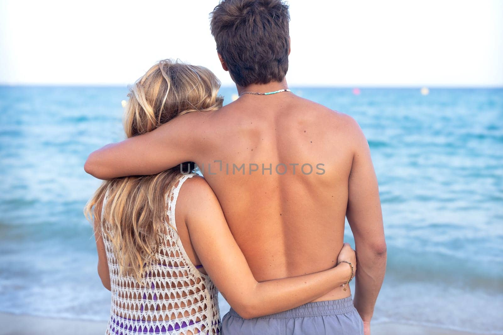 Rear view smiling multiethnic woman and man enjoying vacation. Beautiful and cheerful couple of generation z pose for a photo with a mobile phone.