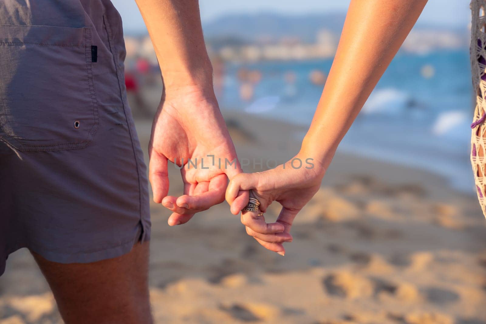 Happy couple in love holding hands and looking at each other on the seashore. A man and a woman are standing on the sand near the ocean. Vows and promises on the seashore.