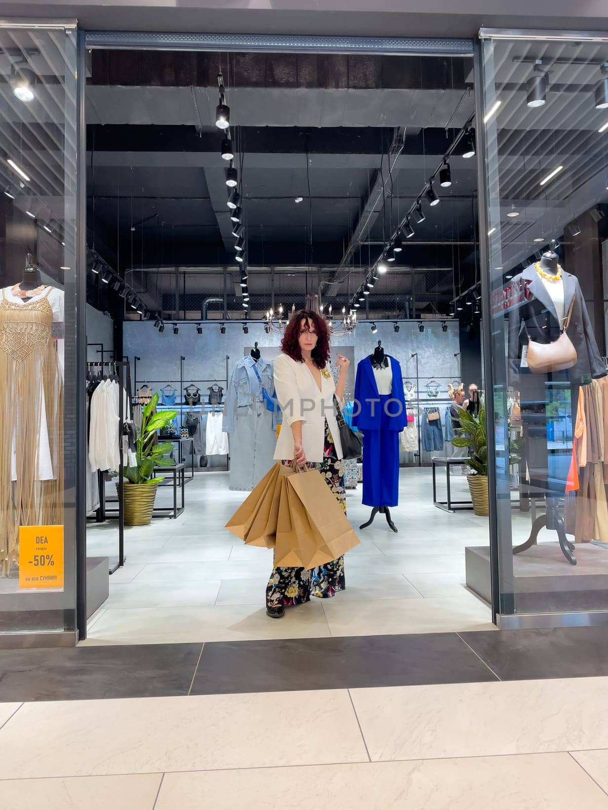 Shopping woman, women's fashion clothes in a store, boutique. Woman choosing clothes in a store.