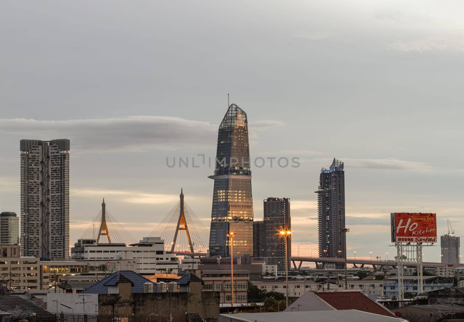Bangkok, Thailand - Aug 14, 2024 - City view with KingBridge tower alongside the iconic landmark of Bhumibol Bridge. Stunning At Twilight skyline of bangkok business district with Skyscrapers use it as your wallpaper, poster and banner design, Selective focus.