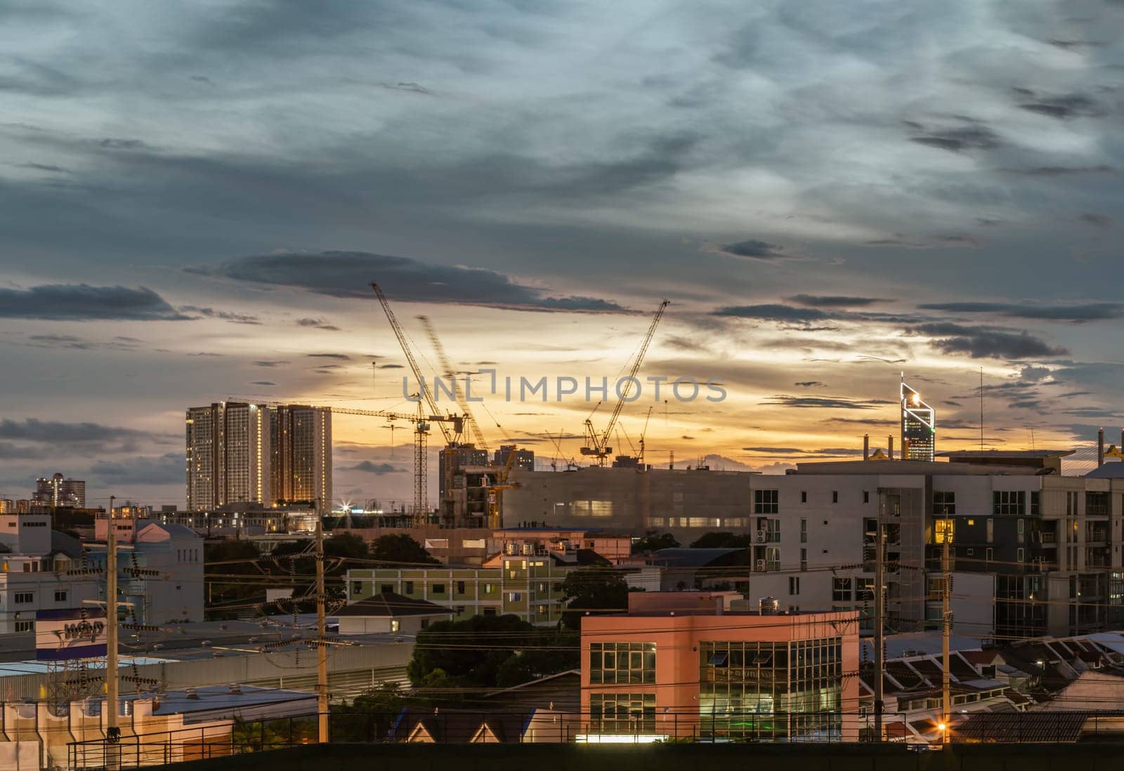Bangkok, Thailand - Aug 14, 2024 - Night city view of Construction of tall buildings with a crane and background of Dramatic sky in the city of Bangkok. Tower crane, Construction cranes, Construction and urban development. use it as your Wallpaper, Poster and Space for text, Selective focus.