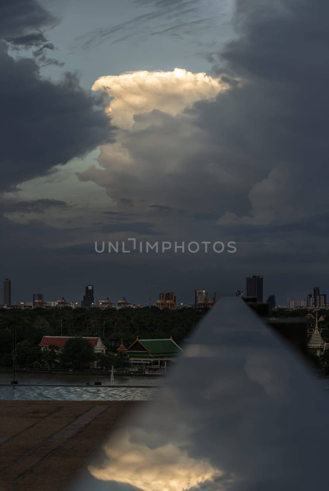 The sky is being covered with amazing clouds with reflection on stainless steel handrail with city view alongside river. Concept idea of Imaginative clouds background, Nature abstract composition for wallpaper and text, Selective focus.