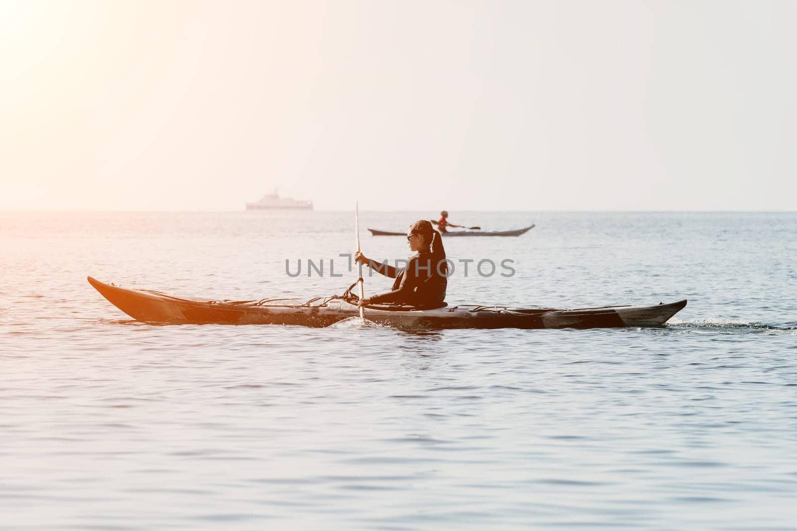 Happy smiling woman in kayak on ocean, paddling with wooden oar. Calm sea water and horizon in background