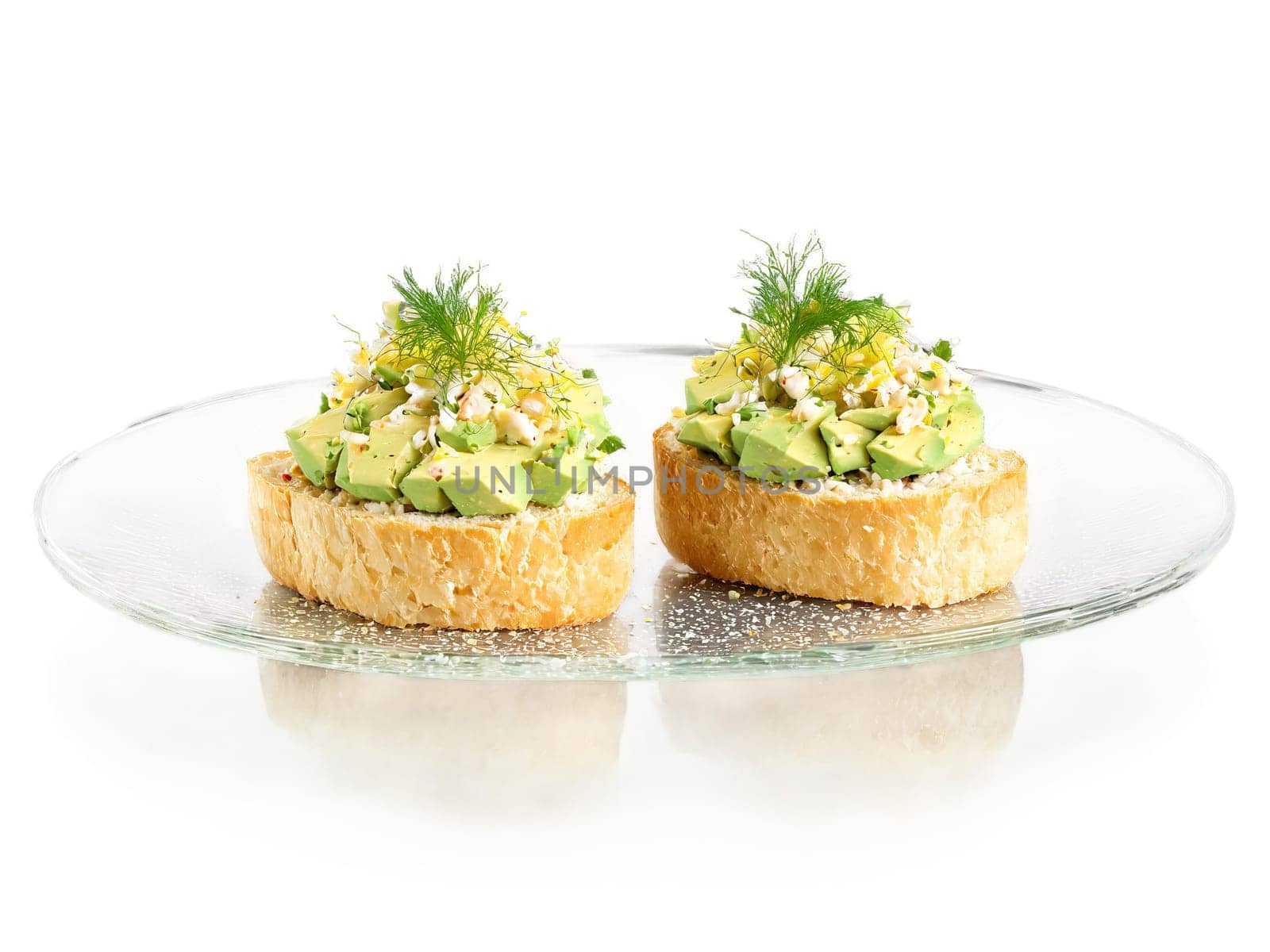 Canapes crab salad with avocado on a toasted crostini served on a transparent glass tray. Food isolated on transparent background.