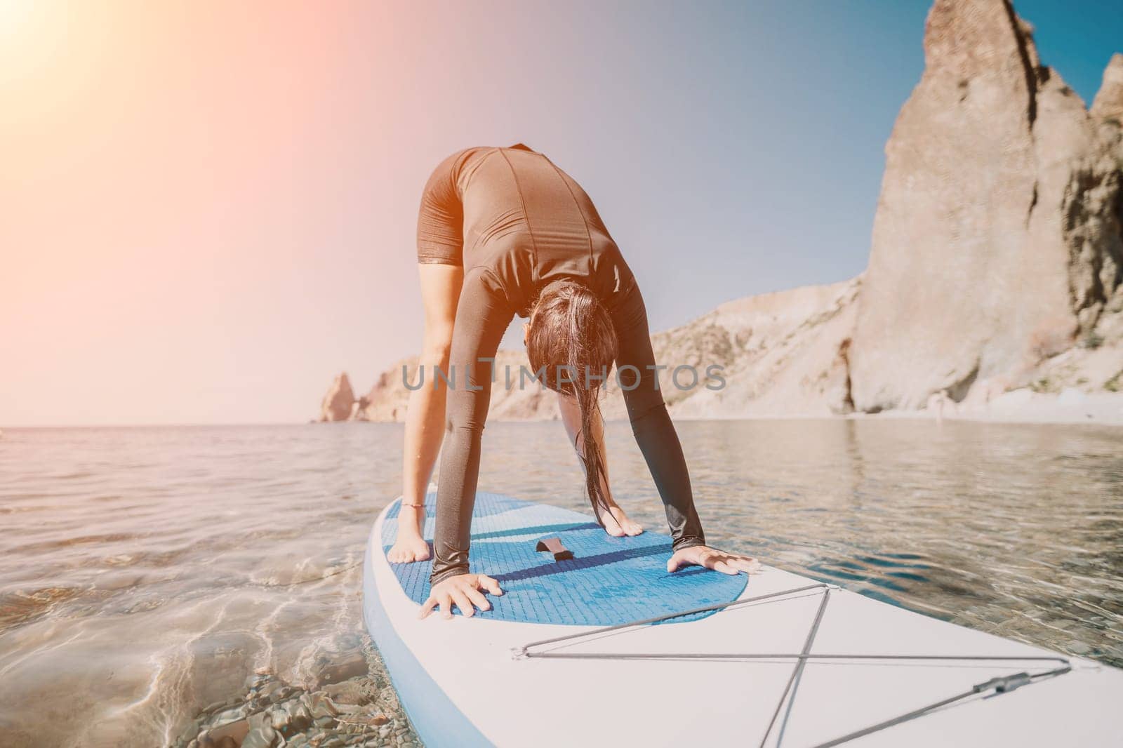 Woman sup yoga. Middle age sporty woman practising yoga pilates on paddle sup surfboard. Female stretching doing workout on sea water. Modern individual hipster outdoor summer sport activity